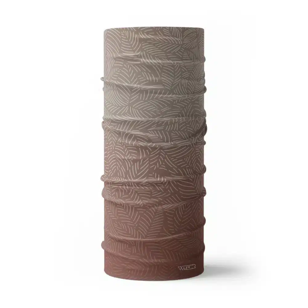 image of a tubular neck gaiter with a crisp leaf pattern overlaid on a gradient background. The colors used in the gradiant are dune, putty and cedar.