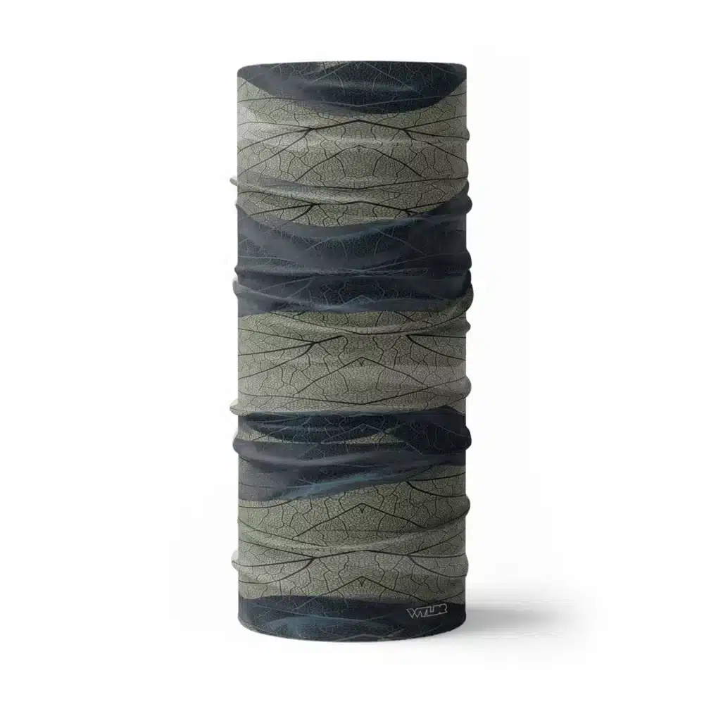 an image of a full neck gaiter. The design features lines and breaks to recreate the look of a leaf print. The colors behind the print mimic waves. This image showcases colors in cool blues and greens.