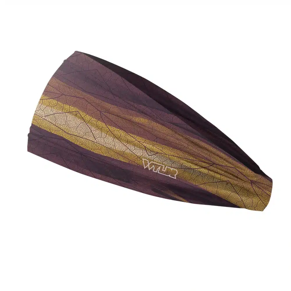 Side view of a headband that is 3 inches at the front and 1 inch in the back to show that it is tapered. The design features lines and breaks to recreate the look of a leaf print. The colors behind the print mimic waves. This image showcases warm purples, oranges and yellows.