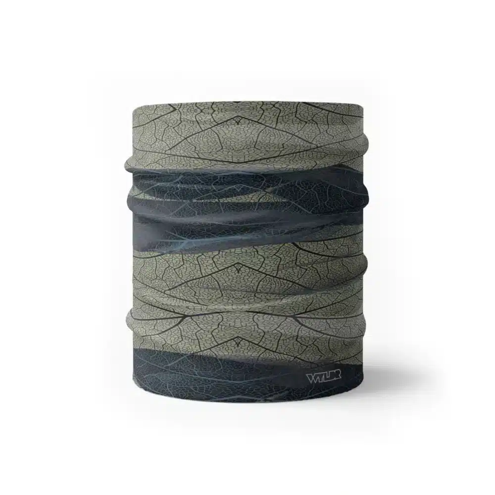 an image of a half neck gaiter. The design features lines and breaks to recreate the look of a leaf print. The colors behind the print mimic waves. This image showcases colors in cool blues and greens.