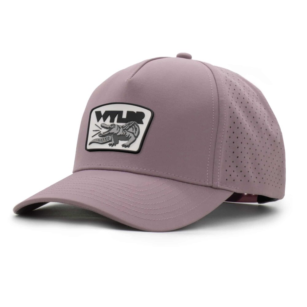 three-quarter view of a 5 panel, water resistant, floatable hat with a PVC patch. the patch is a gator catching a golf ball in its mouth and features the brand name, Wyldr. the hat is lilac purple