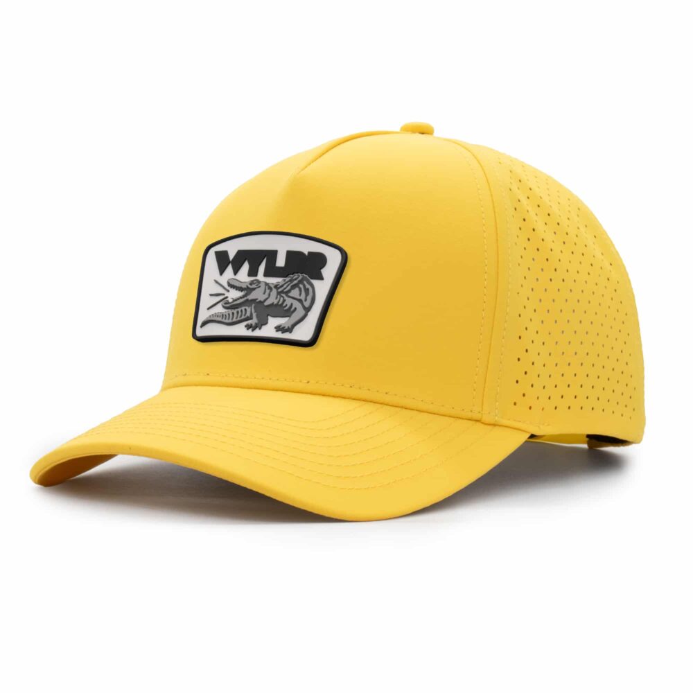 three-quarter view of a 5 panel, water resistant, floatable hat with a PVC patch. the patch is a gator catching a golf ball in its mouth and features the brand name, Wyldr. the hat is yellow