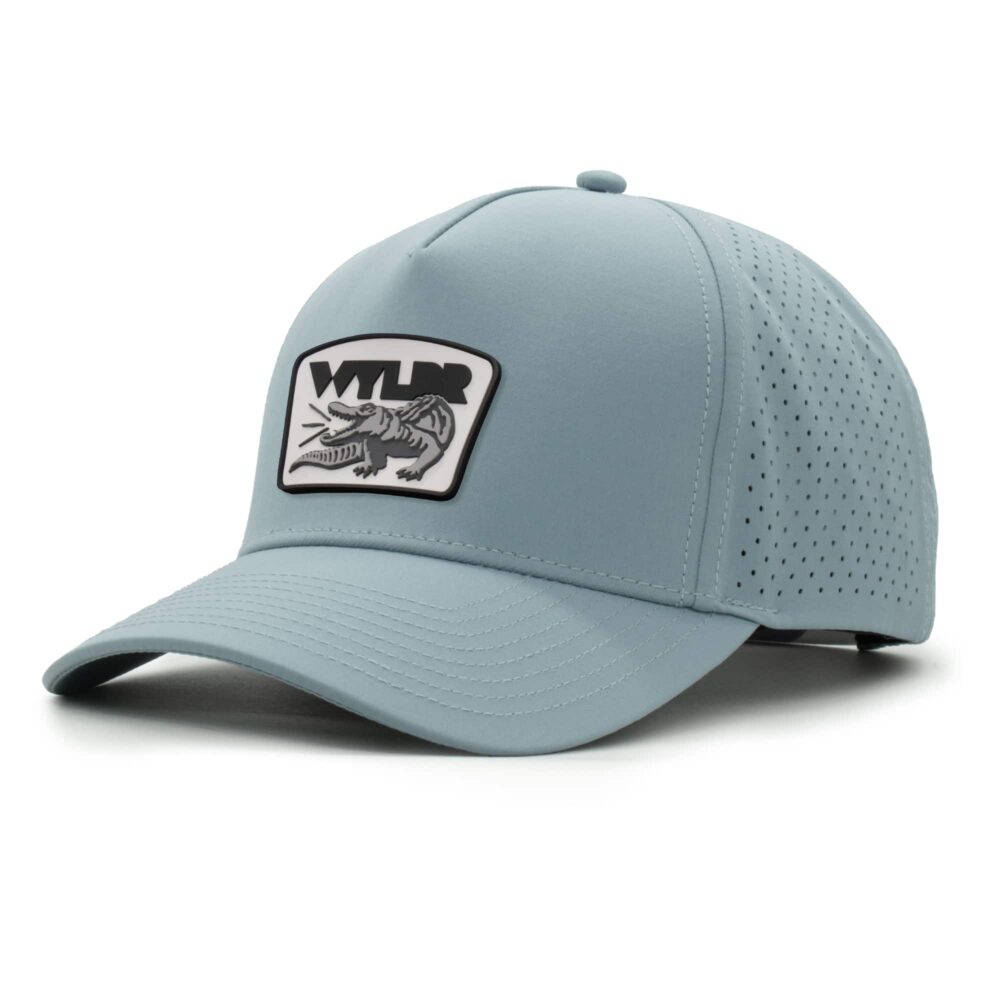 three-quarter view of a 5 panel, water resistant, floatable hat with a PVC patch. the patch is a gator catching a golf ball in its mouth and features the brand name, Wyldr. the hat is light blue