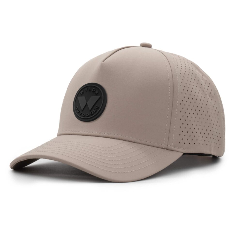 three-quarter view of a 5 panel, water resistant, floatable hat with a PVC patch. the patch is a round medallion featuring the letter W and the text Wyldr Outdoors. the hat is a warm tan color.