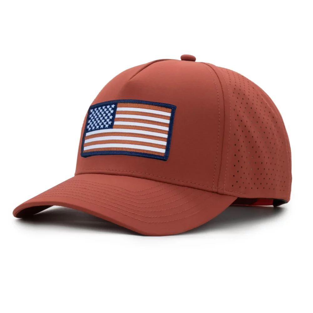three-quarter view of a 5 panel, water resistant, floatable hat with an embroidered american flag patch. the hat is an orange-rust color.