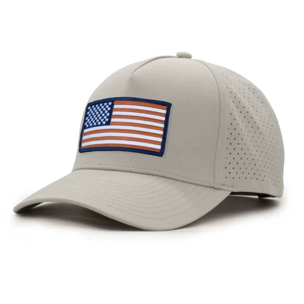 three-quarter view of a 5 panel, water resistant, floatable hat with an embroidered american flag patch. the hat is a light tan color.