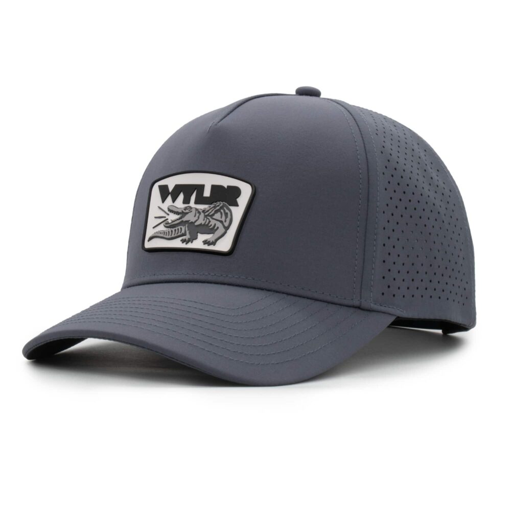 three-quarter view of a 5 panel, water resistant, floatable hat with a PVC patch. the patch is a gator catching a golf ball in its mouth and features the brand name, Wyldr. the hat is a dark blue-gray color