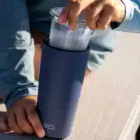 An image of a person removing the glass insert from the powder-coated, stainless steel portion of a DUUN tumbler.